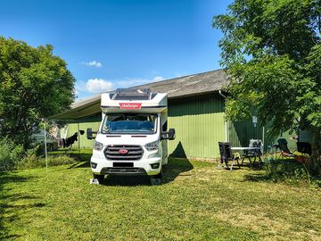 Grass touring pitch surrounded by greenery