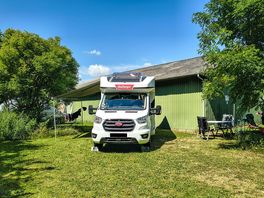 Grass touring pitch surrounded by greenery